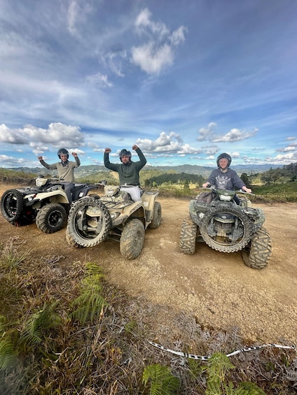 Three people on ATVs in a natural landscape with mountains in the background. 1