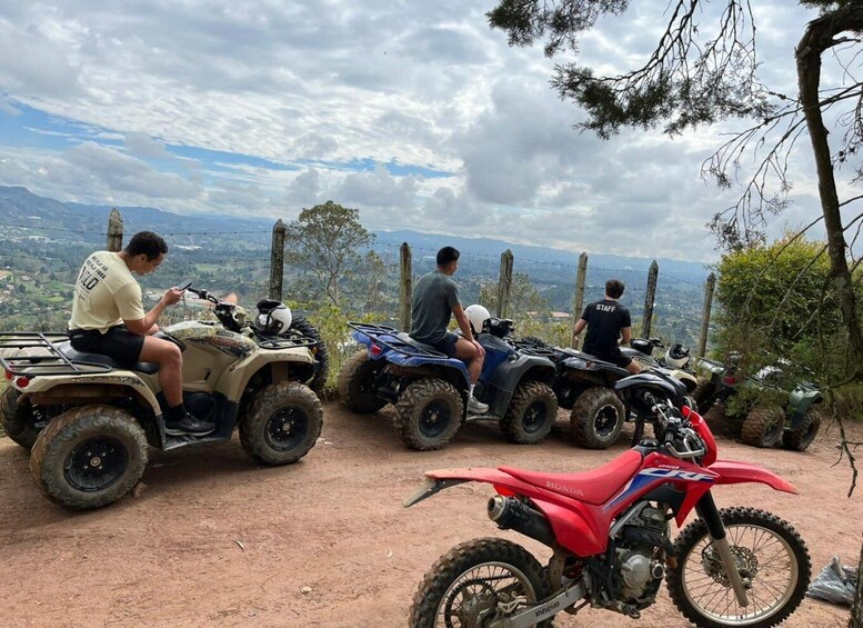 Four off-road vehicles parked on a dirt path with a scenic view of a mountainous landscape. 4