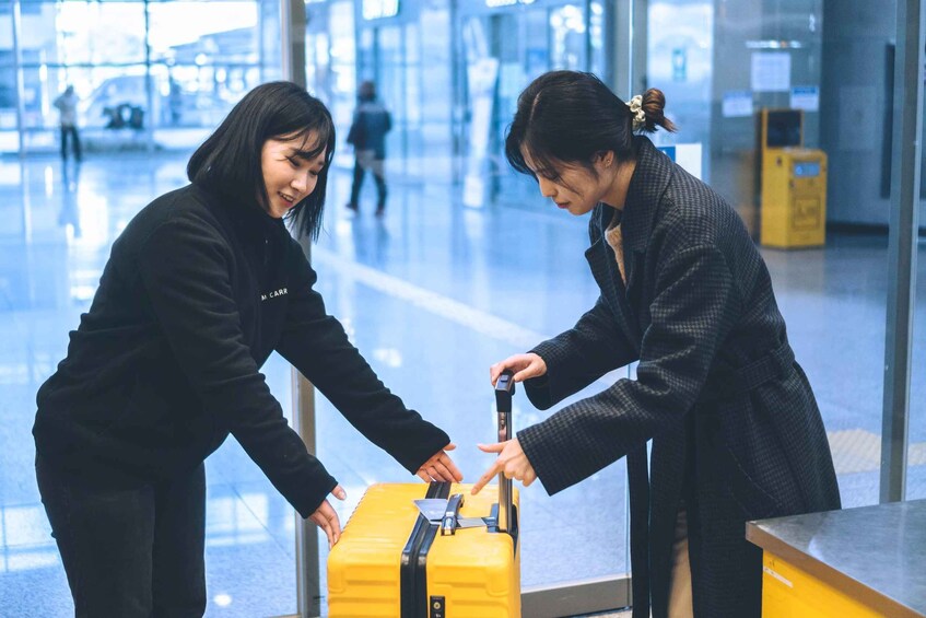 Two individuals handling a yellow suitcase at an airport. 5