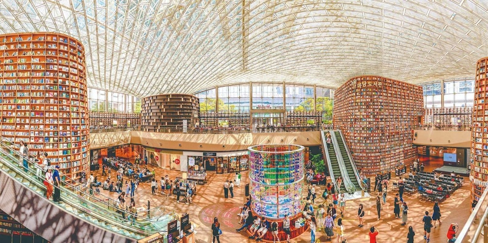 A large indoor library with multiple levels, bookshelves, and a central colorful sculpture. 5