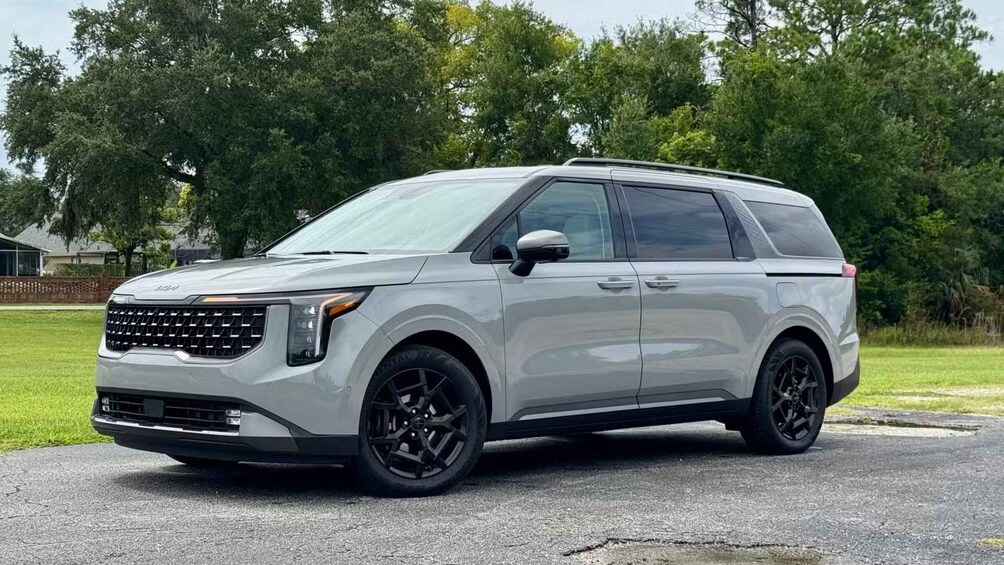 A silver SUV parked on a driveway with a green lawn and trees in the background. 4
