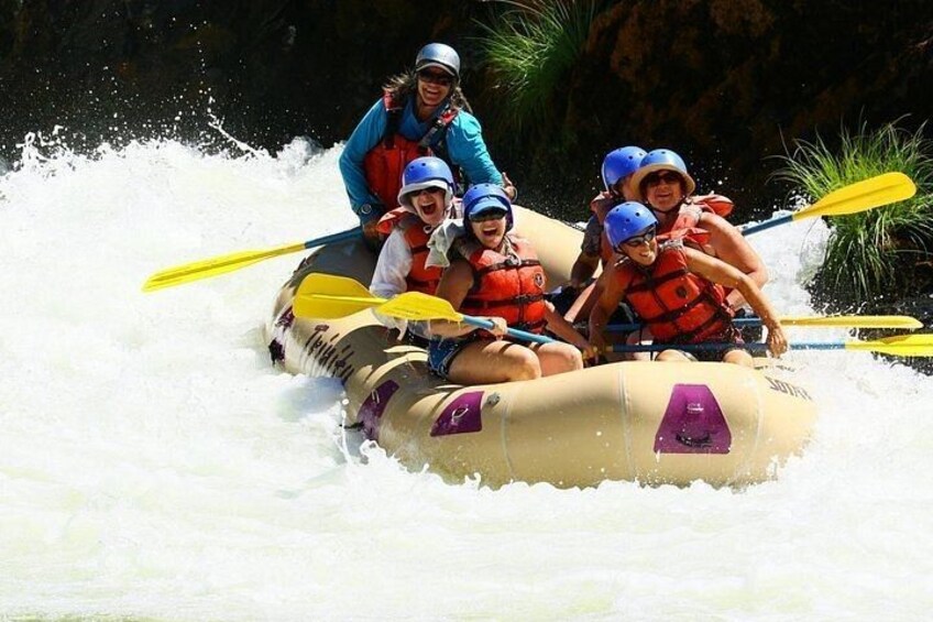 A group of people in a raft navigating through white water rapids. 4