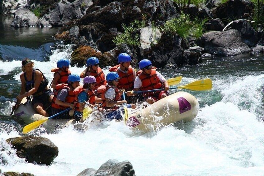 A group of people in a raft navigating a river with rapids. 3