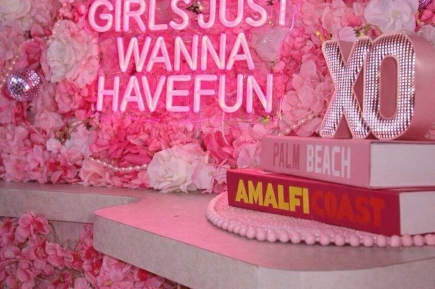 A pink floral backdrop with 'GIRLS JUST WANNA HAVE FUN' and 'X10' signage, along with 'PALM BEACH' and 'AMALFI COAST' on a cake. 4