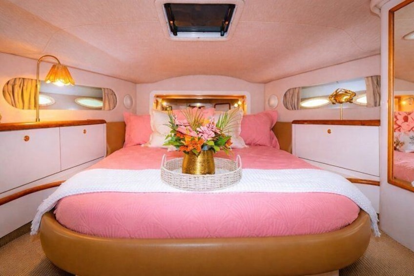A pink-themed bedroom with a bed, bedside lamps, and a decorative vase on the bed. 2