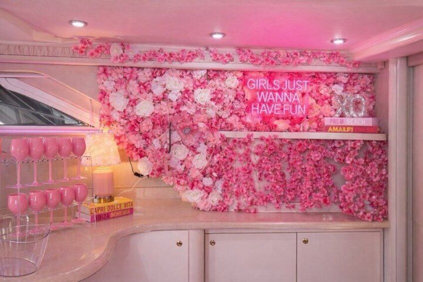 A pink-themed room with a floral wall, pink glasses, and a 'Girls Just Wanna Have Fun' sign. 3