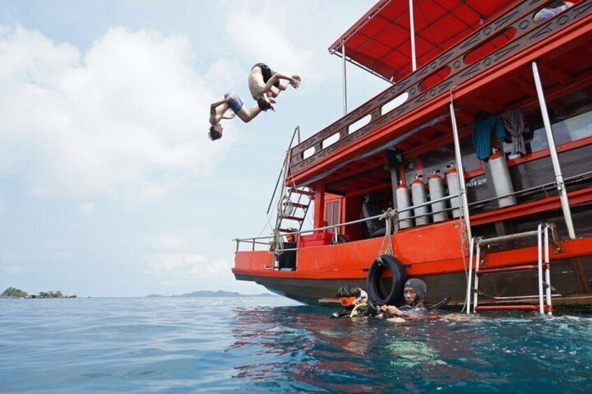 A person diving off a red boat into the water. 1