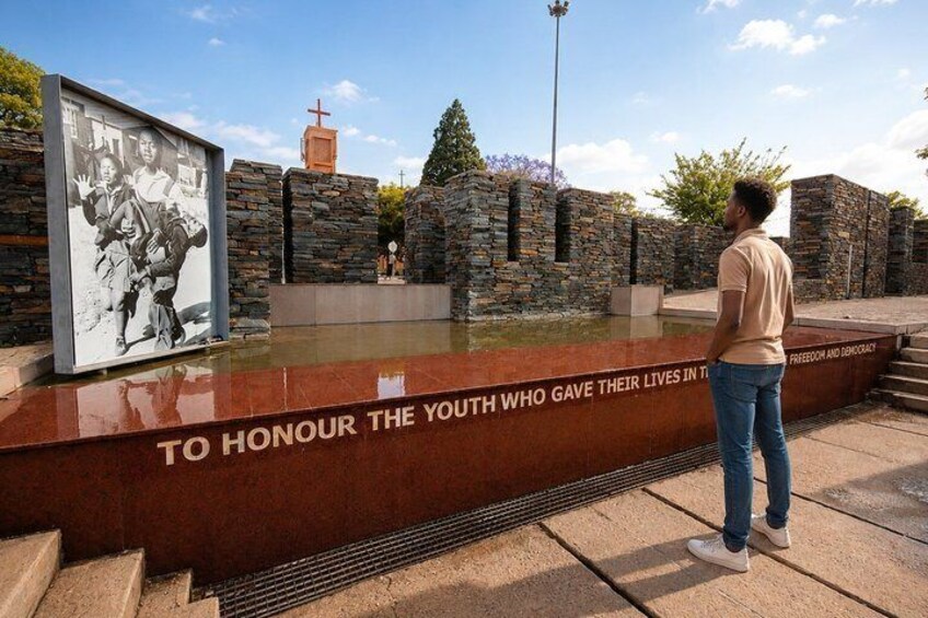 A memorial with a reflective pool, a cross, and a plaque honoring youth. 2
