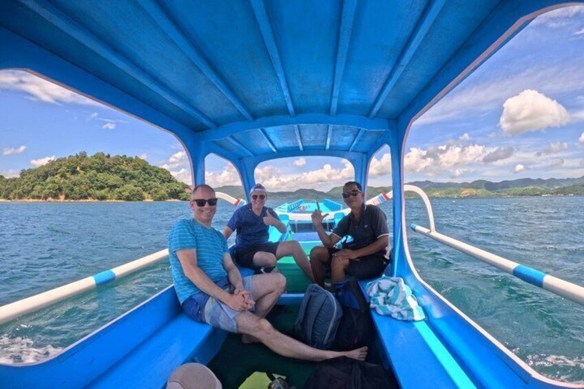A boat with three people on board, water, and a distant green landmass. 2
