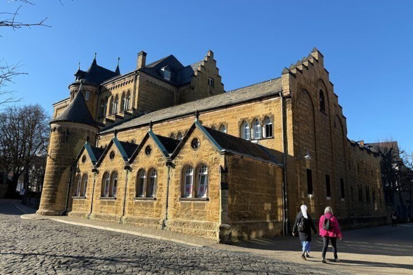 A historic stone building with a turret and arched windows. 1
