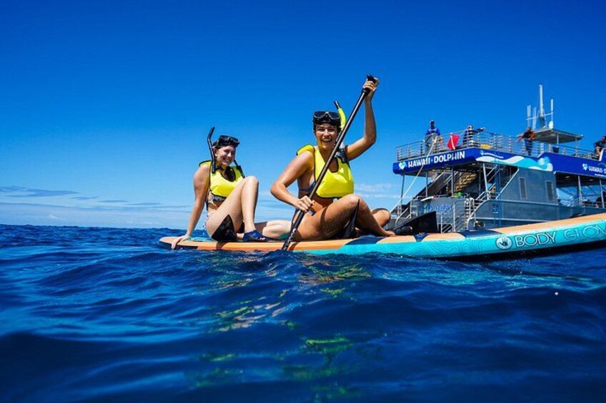 Two people on a paddleboard in the ocean, a boat with 'HAWAII DOLPHIN' written on it, and a clear blue sky. 5