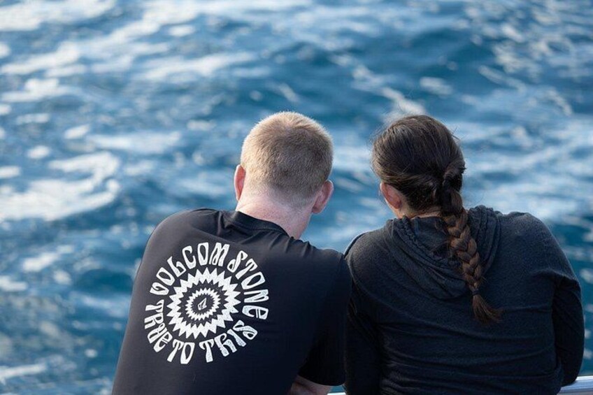 Two people sitting on a boat, facing the ocean. 2