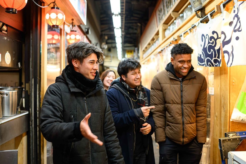 A group of people standing in a narrow alleyway with wooden walls and hanging lanterns. 2