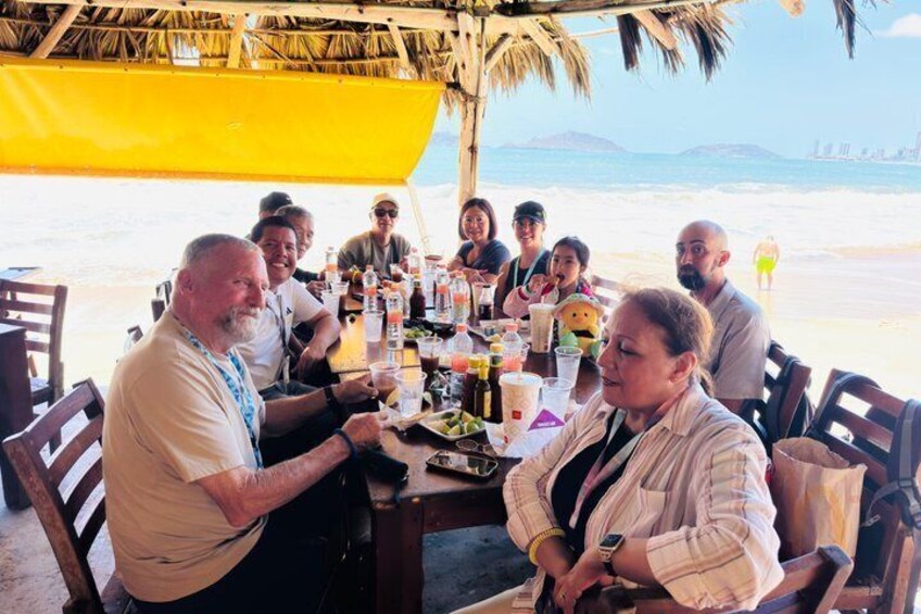 A group of people dining at a beachside table with a view of the ocean. 3
