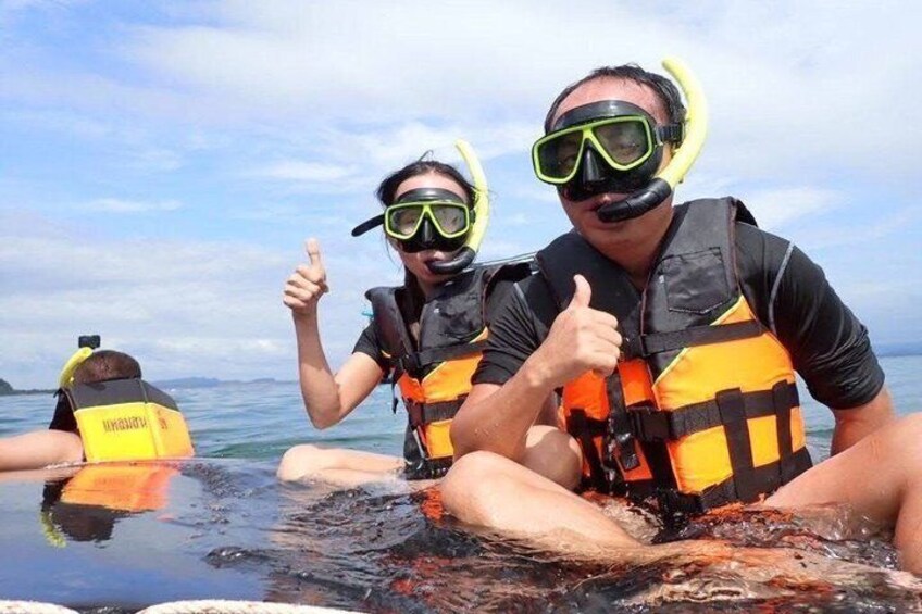 Two people in a boat wearing life jackets and diving gear, giving a thumbs up. 1