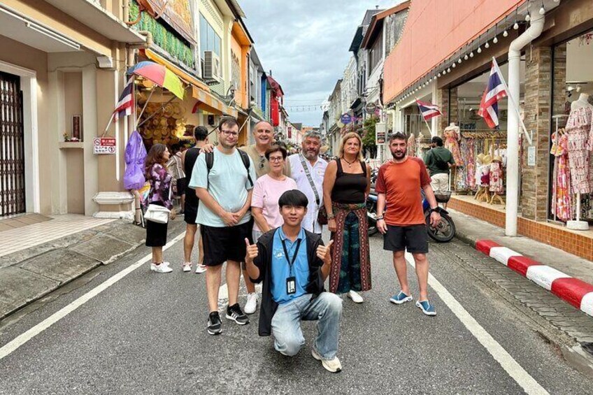 A group of people standing on a street with shops and flags. 2