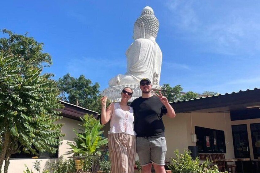 Two people standing in front of a large white statue. 1