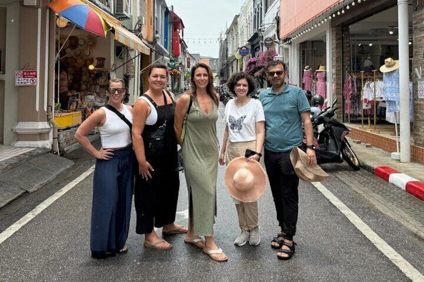 A group of people standing on a street with shops and a motorcycle parked on the side. 3
