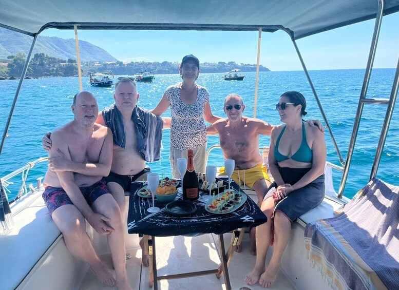 A group of people on a boat with a table set for a meal, surrounded by water and boats in the distance. 2