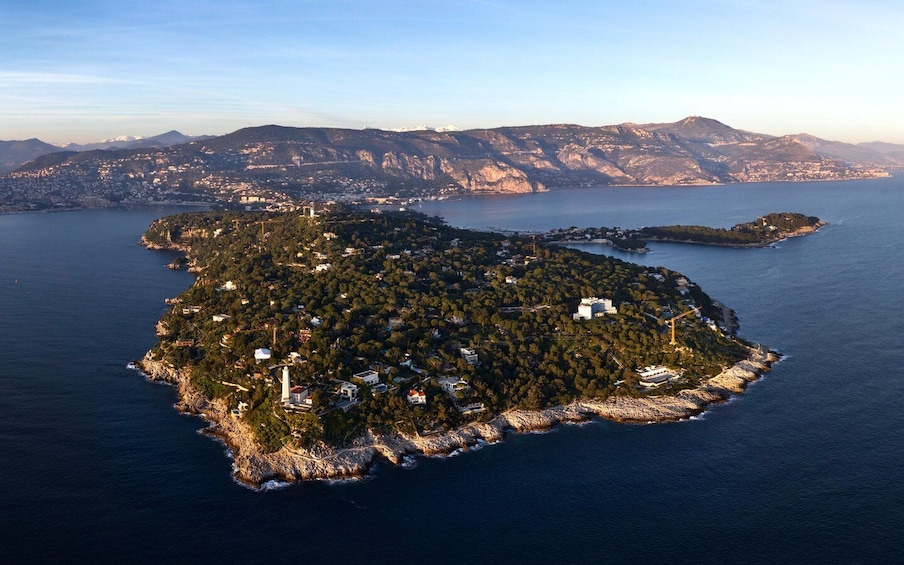 An aerial view of a coastal island with dense vegetation, a lighthouse, and a small settlement. 4