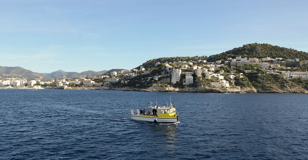 A coastal town with buildings on a hillside and a boat on the water. 5