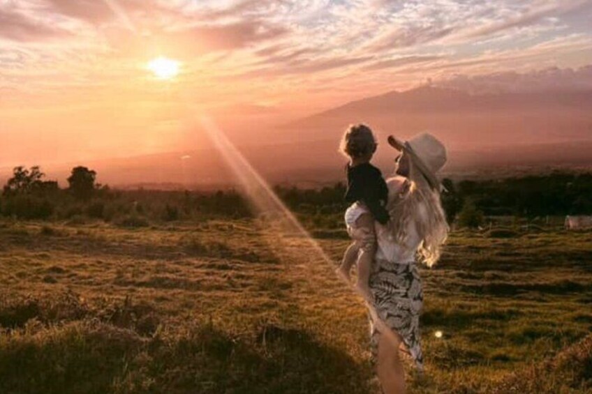A sunset with a person carrying a child in a field. 2