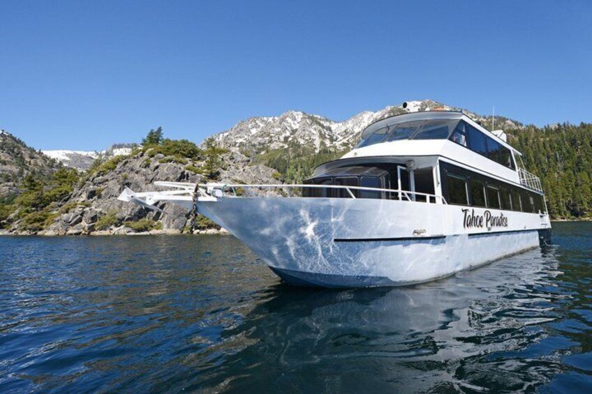 A white boat named Tahoe Paradise on calm water with mountains in the background. 3