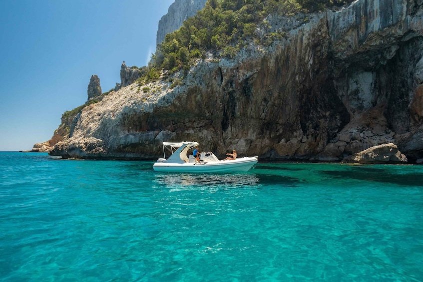 A boat on clear turquoise water with rocky cliffs in the background. 3