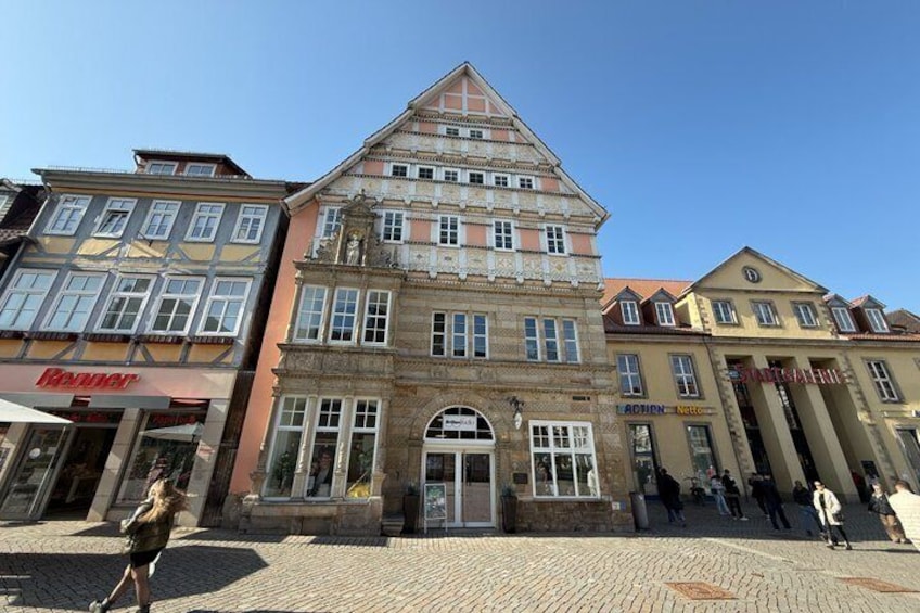 A historic building with a prominent facade, a cobblestone street, and pedestrians. 5