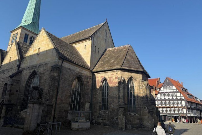 A historic church with a pointed steeple and adjacent traditional half-timbered buildings. 4