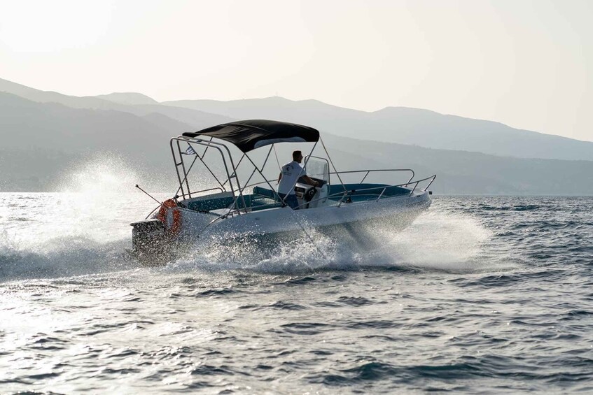 A person driving a speedboat on a body of water with mountains in the background. 3