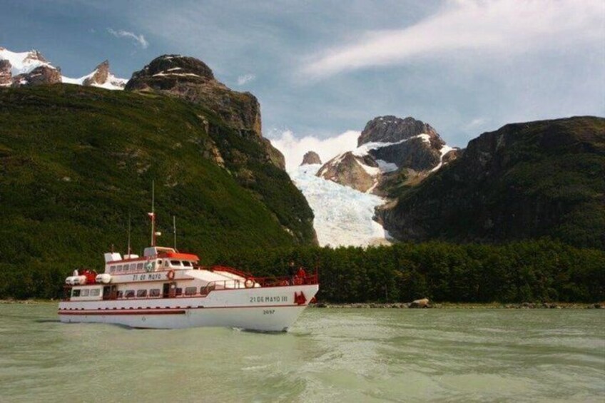 A boat named '21 de Mayo II' on calm waters with a glacier and green mountains in the background. 1