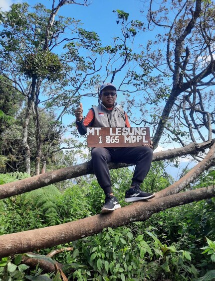 A person sitting on a tree branch with a sign indicating 'MT. LESUNG 1,865 MDPL'. 4