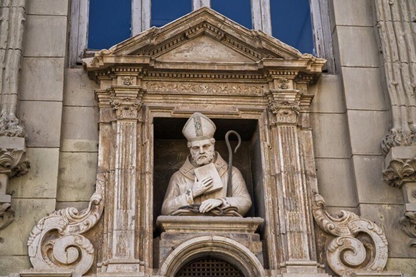 A statue of a figure in a niche with a book, set in a classical architectural structure with columns and a pediment. 4