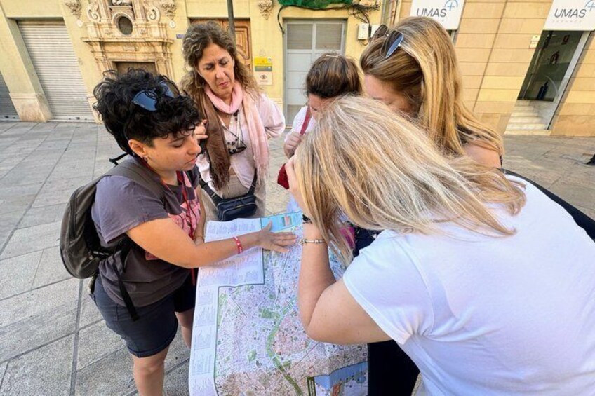 A group of people examining a map outdoors. 1
