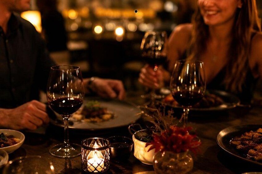 A dimly lit restaurant with candlelight, wine glasses, and a dinner setting. 1