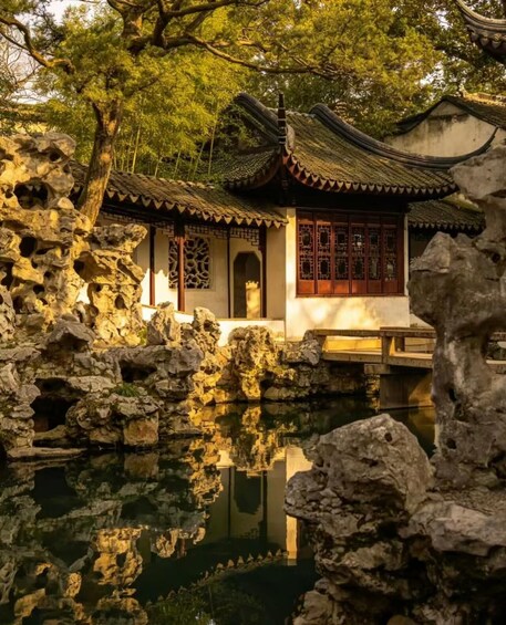 A traditional Chinese building with a tiled roof, surrounded by a rocky pond and trees. 2