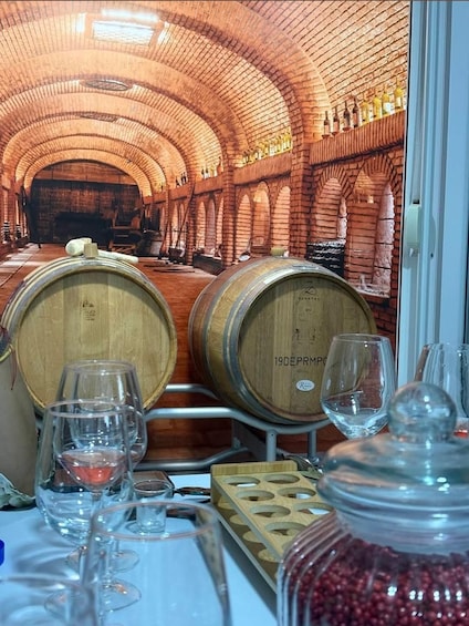 A wine cellar with wooden barrels and wine glasses. 4