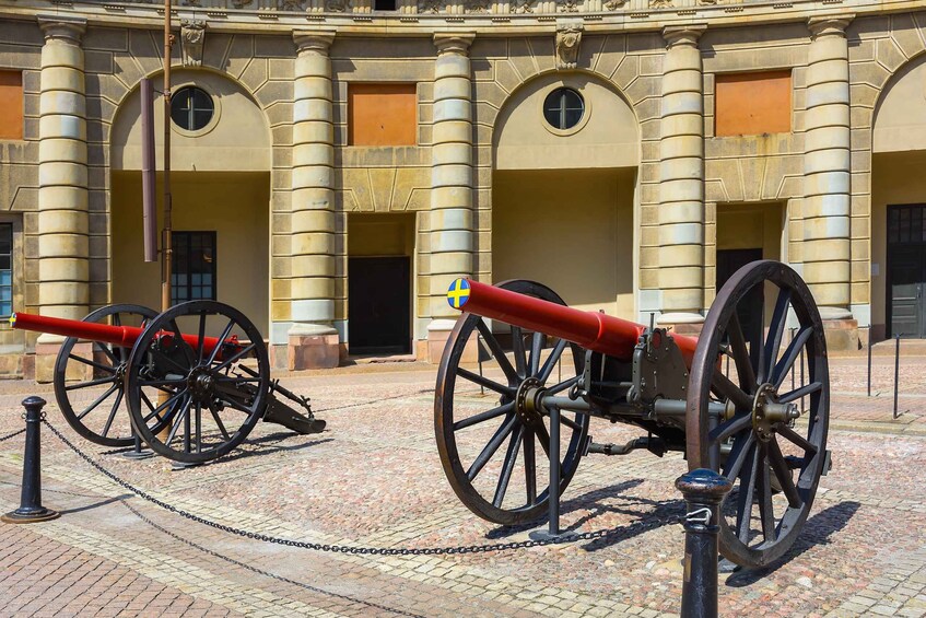 Two cannons in front of a historic building with arched windows and columns. 2