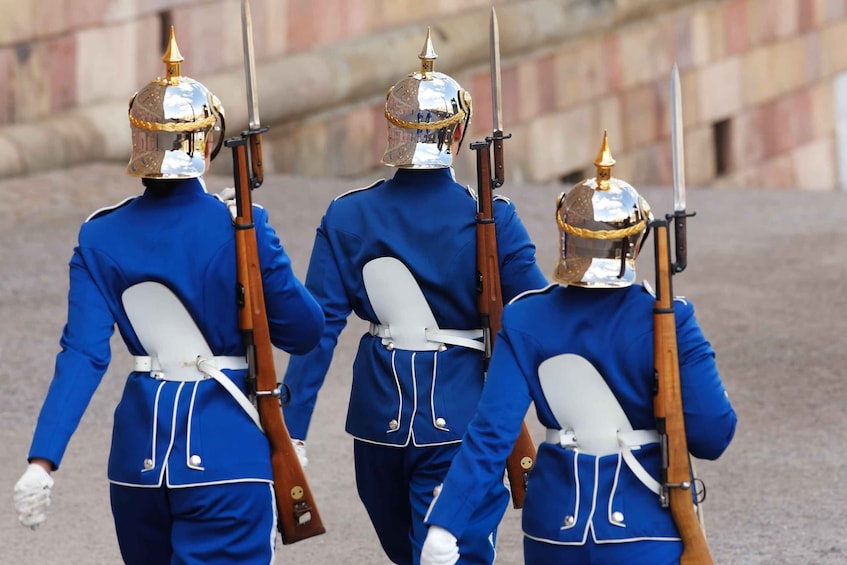 Three guards in blue uniforms with white belts and helmets, carrying rifles and swords. 4