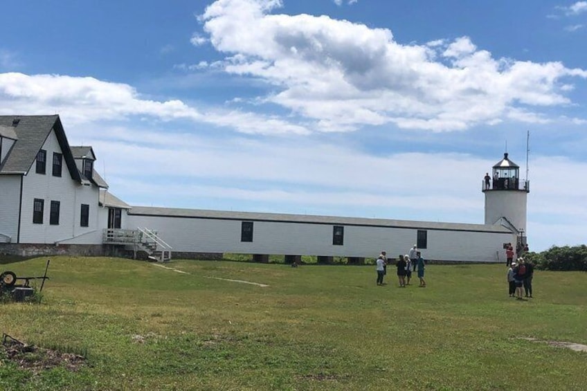 A white building with a lighthouse, a grassy field, and a clear sky. 4