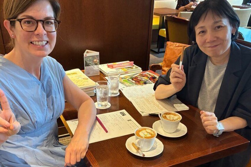 Two people sitting at a table with papers, a cup of coffee, and a smartphone. 1