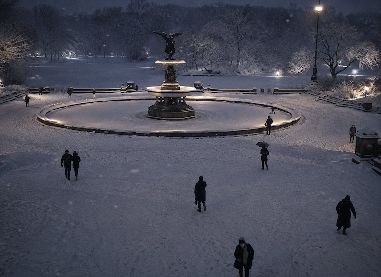 A snow-covered park with a central fountain, people walking, and a bridge in the background. 5