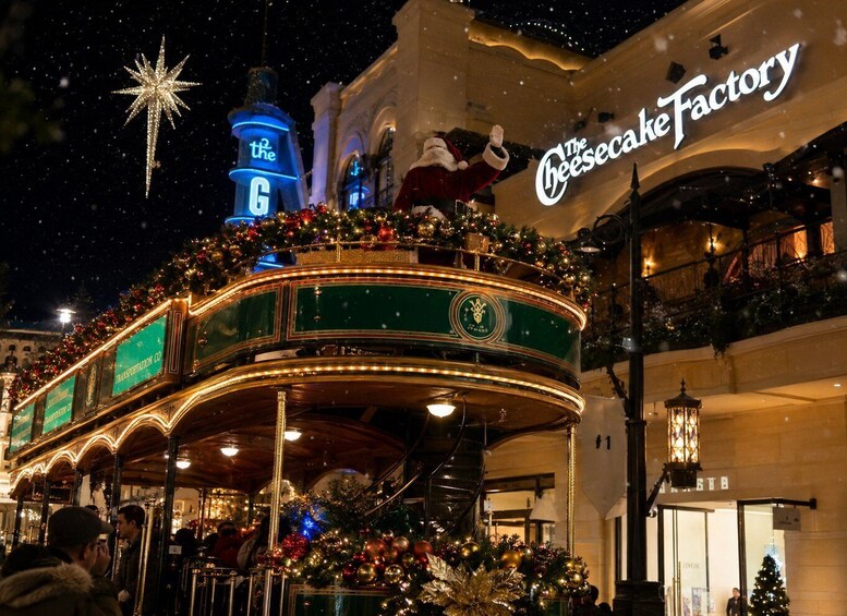 A festive carousel with Christmas decorations, a sign for 'The Cheesecake Factory,' and a blue star in the night sky. 1