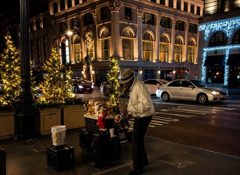 A street musician playing a saxophone, decorated Christmas trees, and a building with classical architecture. 3