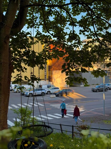 A tree-lined street with a swing set and parked cars. 5