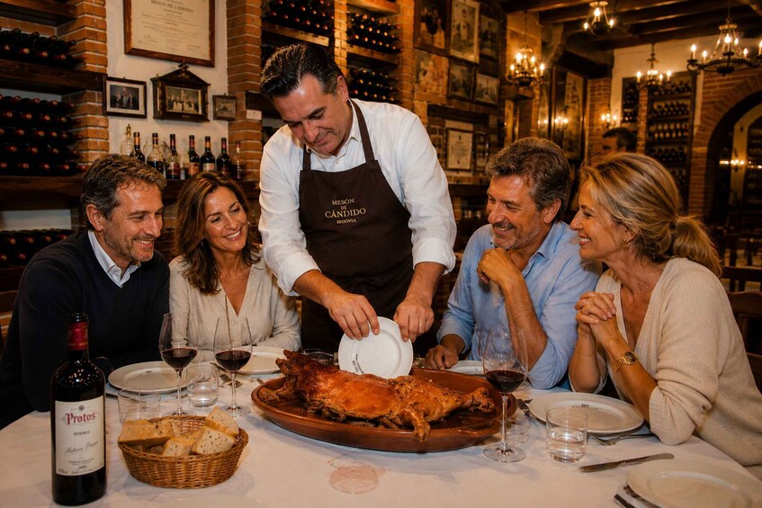 A group of people dining at a restaurant with a roasted pig on the table. 4