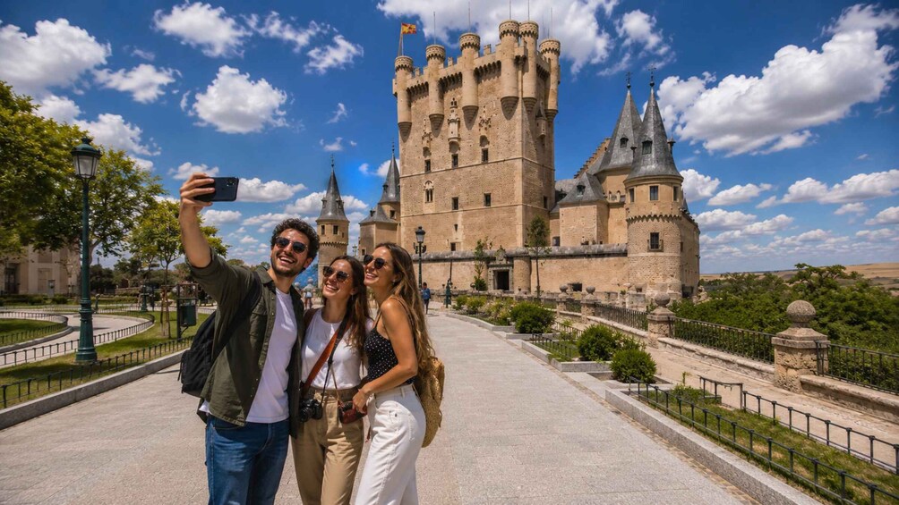 A historic castle with towers, a paved walkway, and a clear blue sky. 1