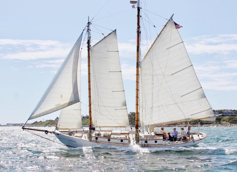 A sailboat with two masts and sails, on a body of water with a clear sky. 5