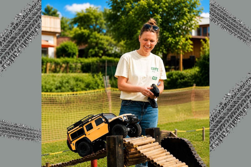 A person with a remote controlling a toy off-road vehicle on a track. 1